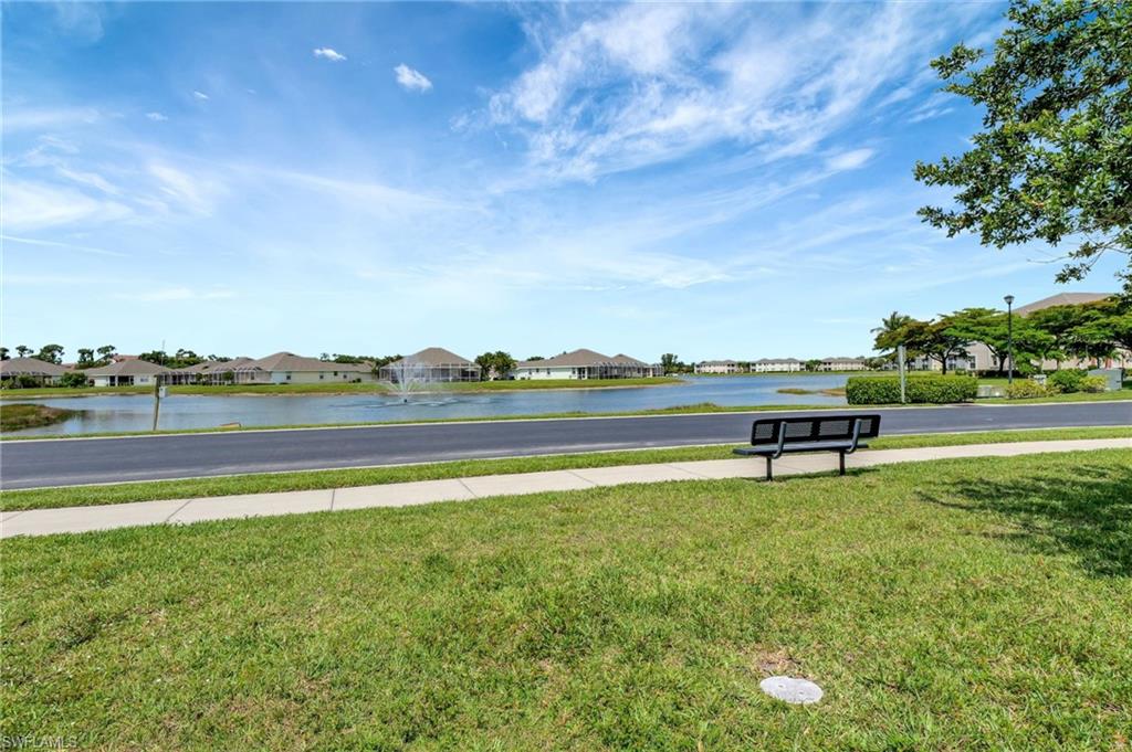 Landscaped common area with a contemporary park bench alongside a paved sidewalk and street