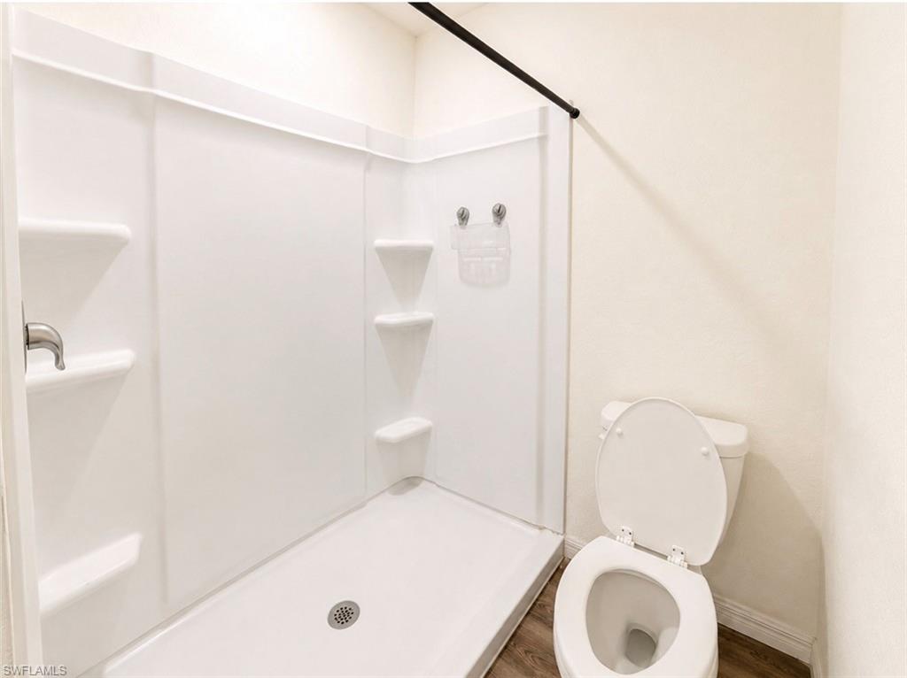 Integrated shower unit with built-in shelving, brushed nickel fixtures, and a coordinating toilet