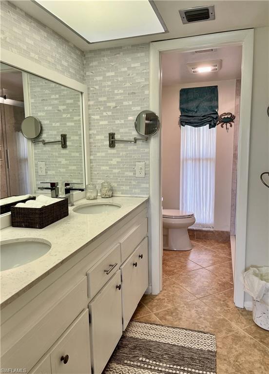 Walk in shower, featuring double vanity, tasteful backsplash, and tile floors