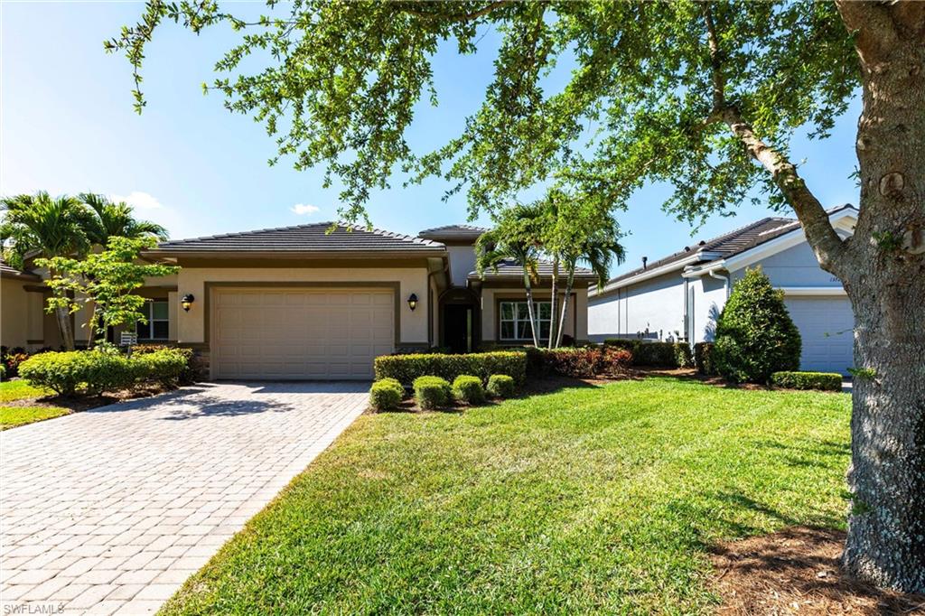 Exterior featuring a neutral-toned stucco facade, stone accents, a paver driveway, and a two-car garage