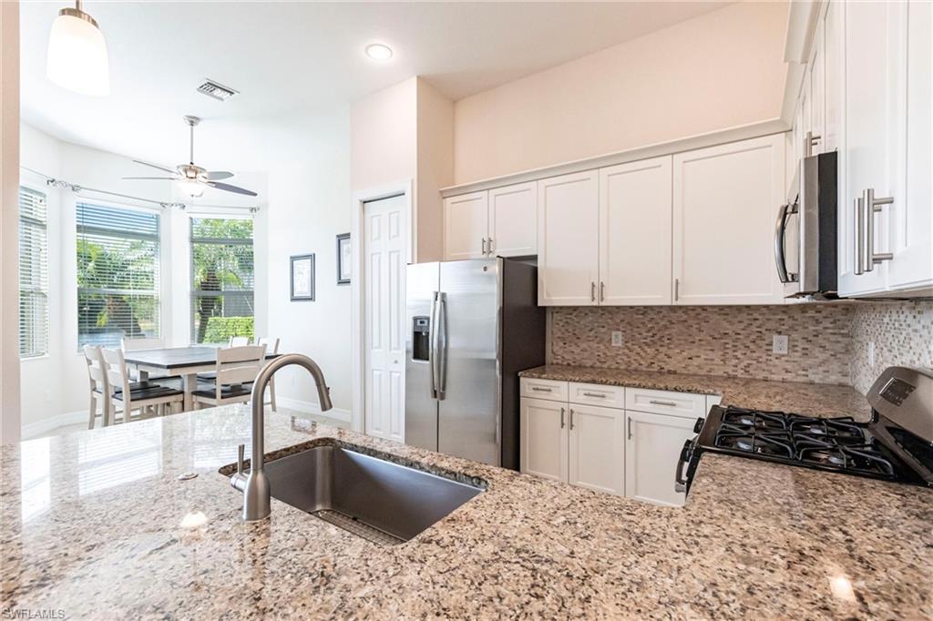 Kitchen featuring light granite countertops, white cabinetry with brushed nickel hardware, and a mosaic tile backsplash