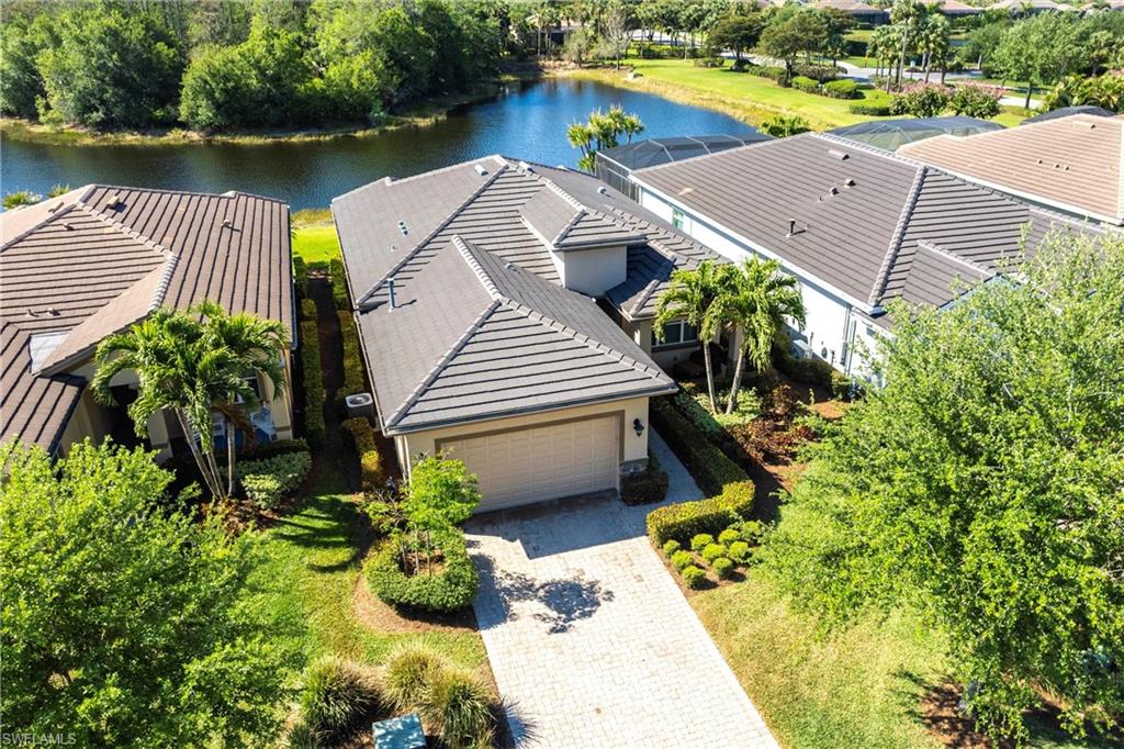 Waterfront property featuring a paver driveway, an attached garage, and mature landscaping