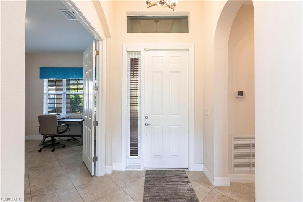 Entryway featuring a paneled door with a sidelight, transom window, and tiled flooring