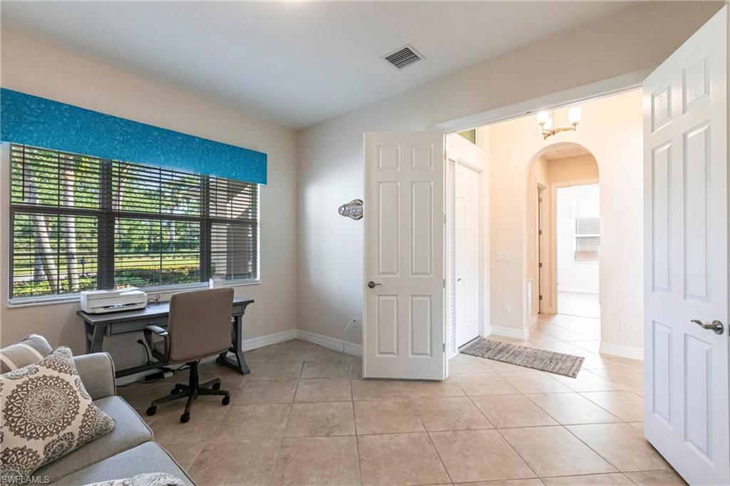 Versatile bonus room featuring large windows with horizontal blinds, tiled flooring, and double entry doors