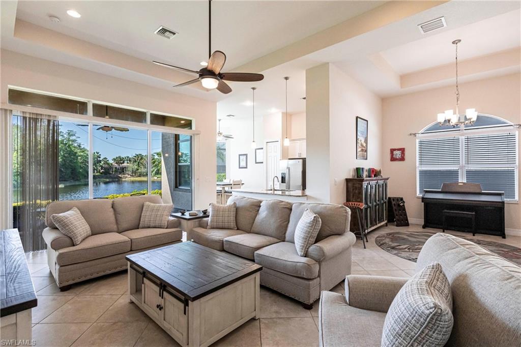 Spacious living area featuring large format tile flooring and a tray ceiling with recessed lighting