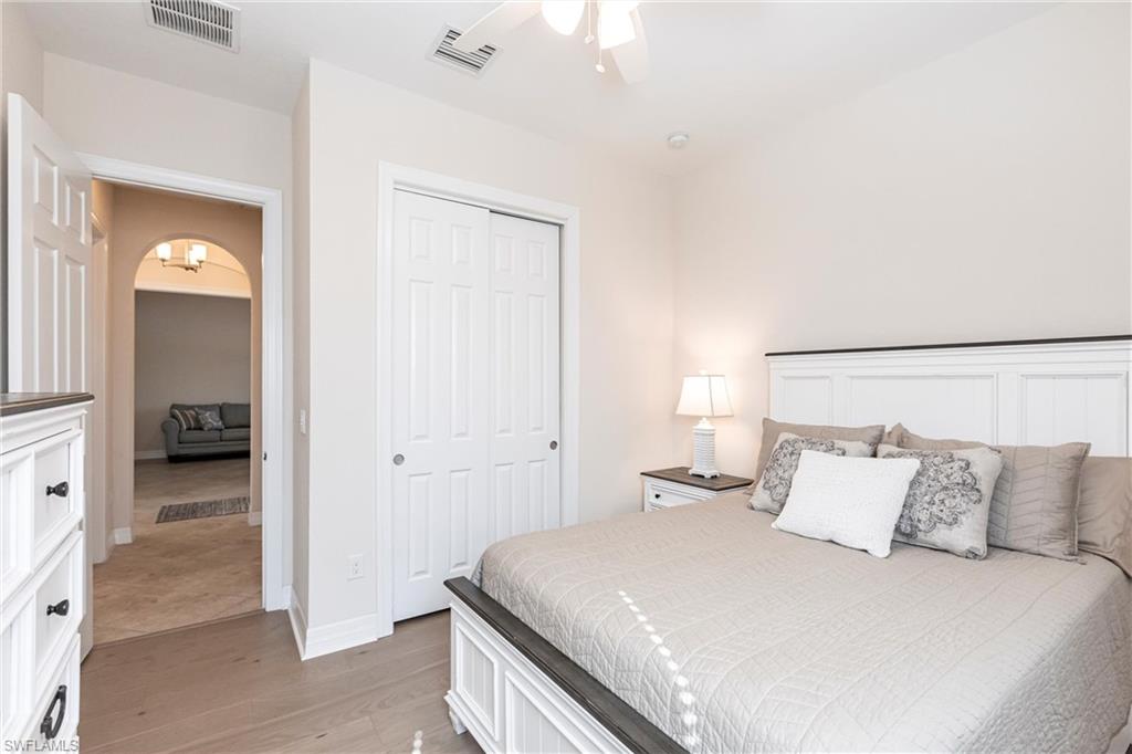 Neutral tone bedroom featuring wood-finish flooring and a ceiling fan