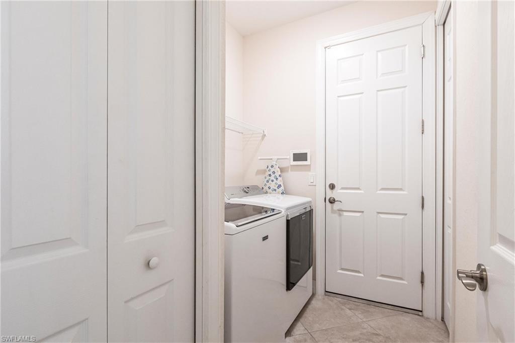 Dedicated laundry area featuring tile flooring and a paneled door
