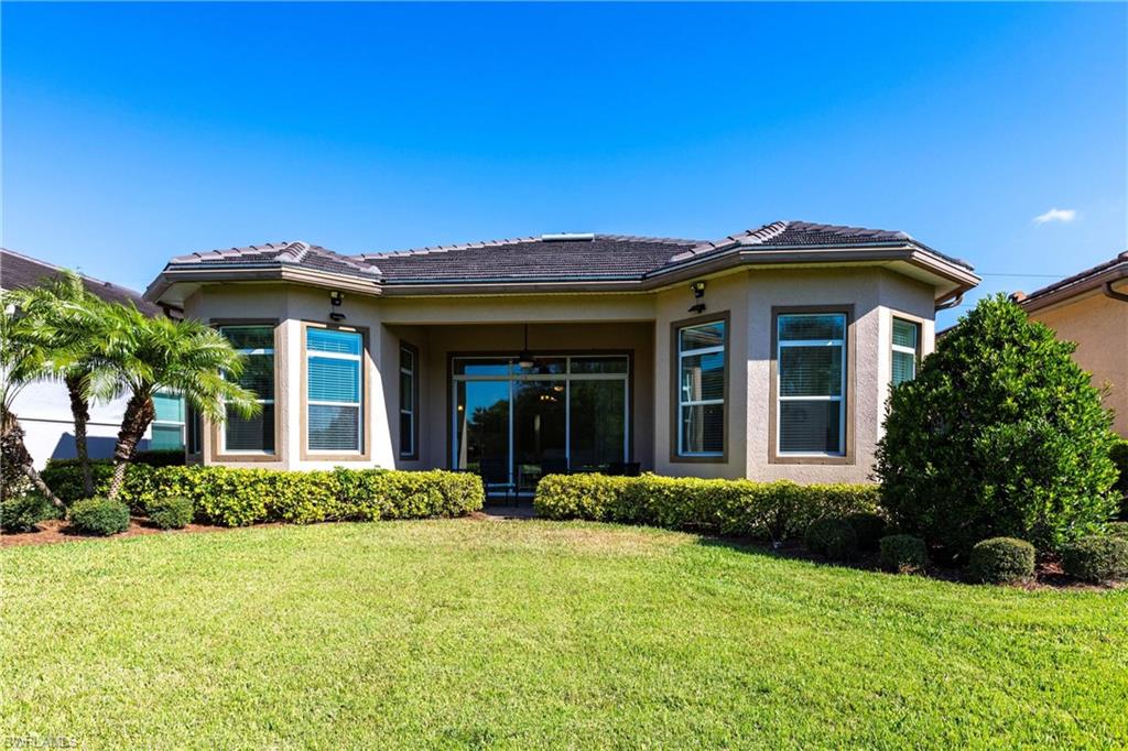 Expansive rear lawn featuring mature landscaping and a covered patio with sliding glass doors