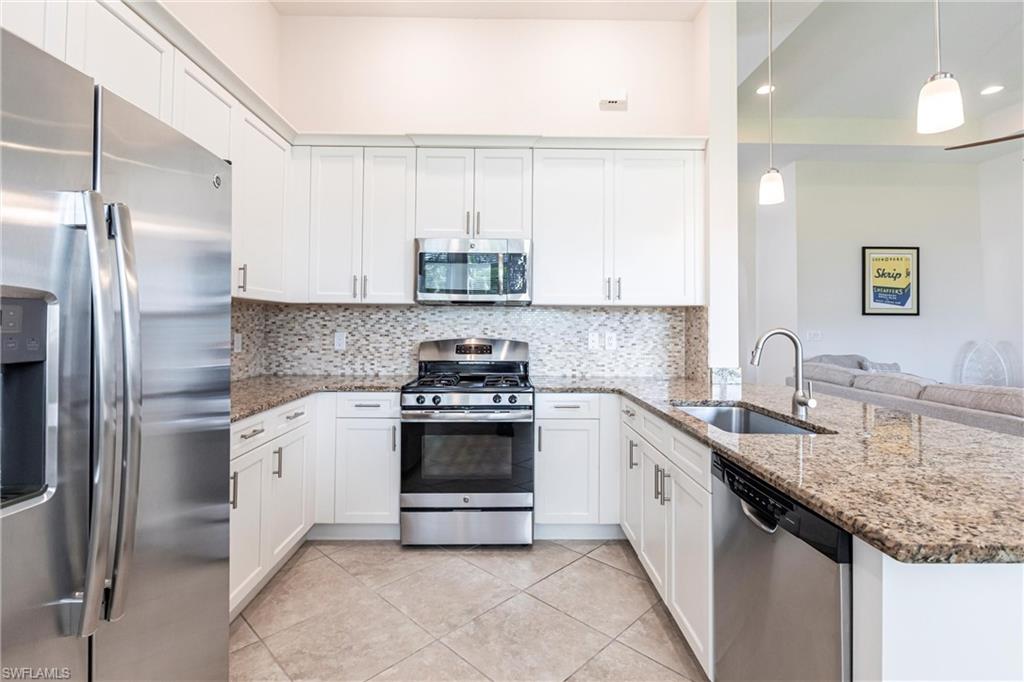 U-shaped kitchen featuring white cabinetry and granite countertops