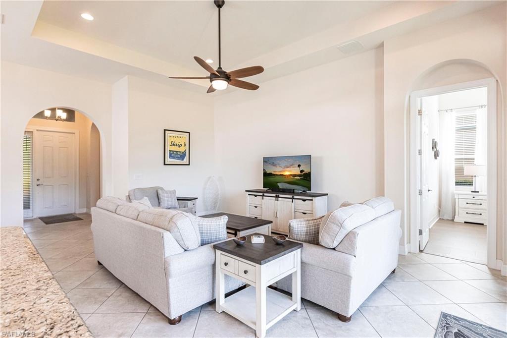 Spacious living area featuring a tray ceiling with recessed lighting and a ceiling fan