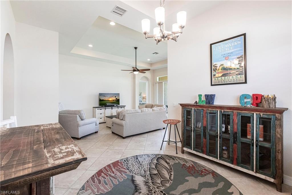 Spacious living area featuring tile flooring, an arched entryway, recessed lighting, and a tray ceiling