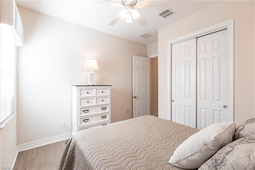 Room featuring wood-finish flooring, a window with blinds, a ceiling fan with integrated lighting, and a closet with bifold doors