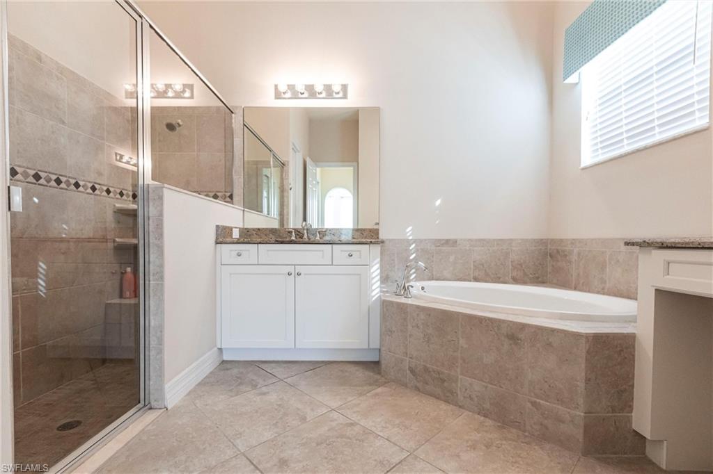 Bathroom featuring a tiled soaking tub and a glass-enclosed shower with tiled walls and a built-in bench