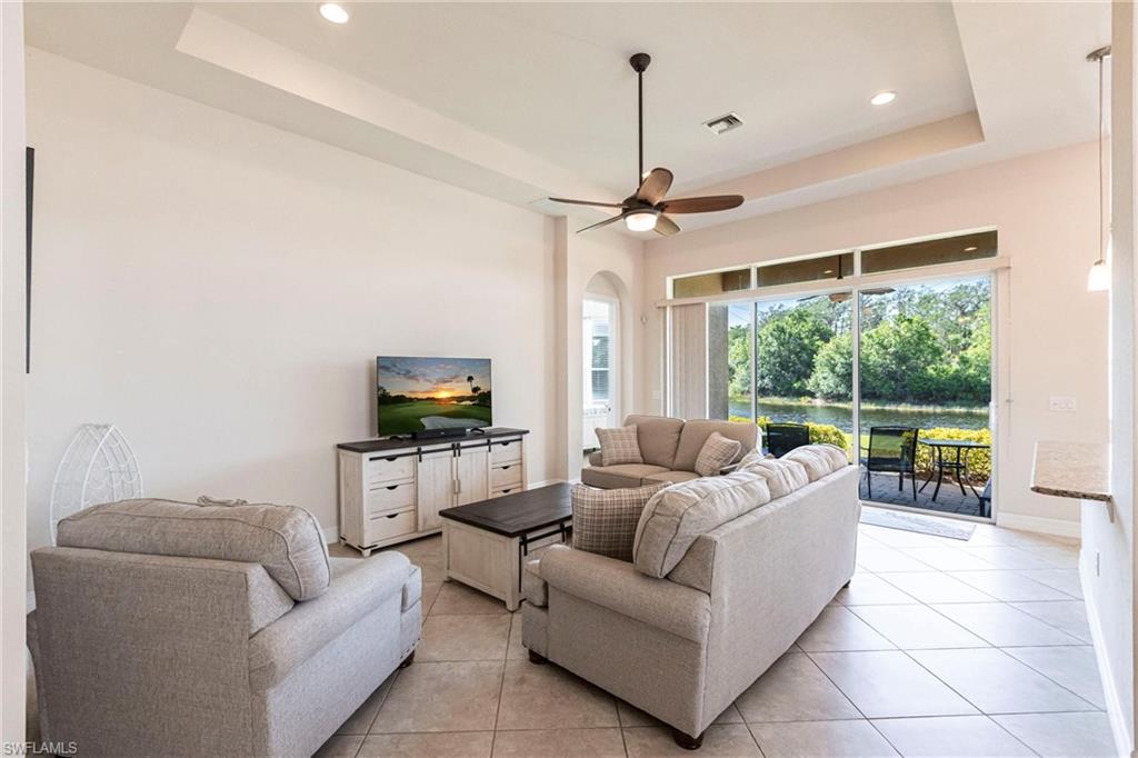 Living area featuring large format tile flooring, a tray ceiling, and a ceiling fan