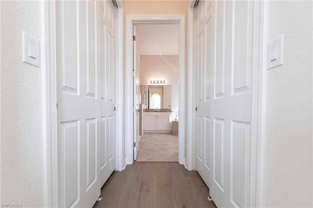 Hallway with wood-finish flooring, flanked by two panel-style bi-fold closet doors