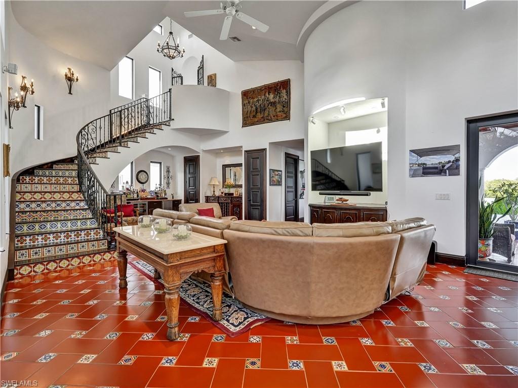 Grand entry featuring a custom wrought iron spiral staircase with patterned tile risers, terracotta tile flooring with accent tiles, and a double-height ceiling