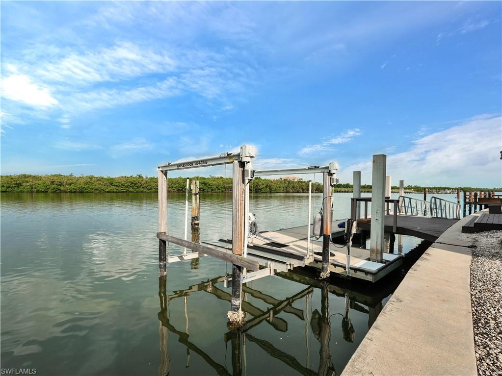 Waterfront dock with a boat lift, composite decking, and concrete seawall