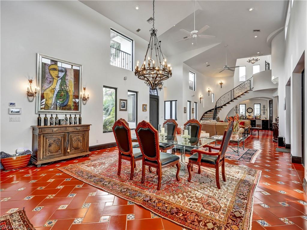 Dining area with high ceilings featuring a grand chandelier and terracotta tile flooring