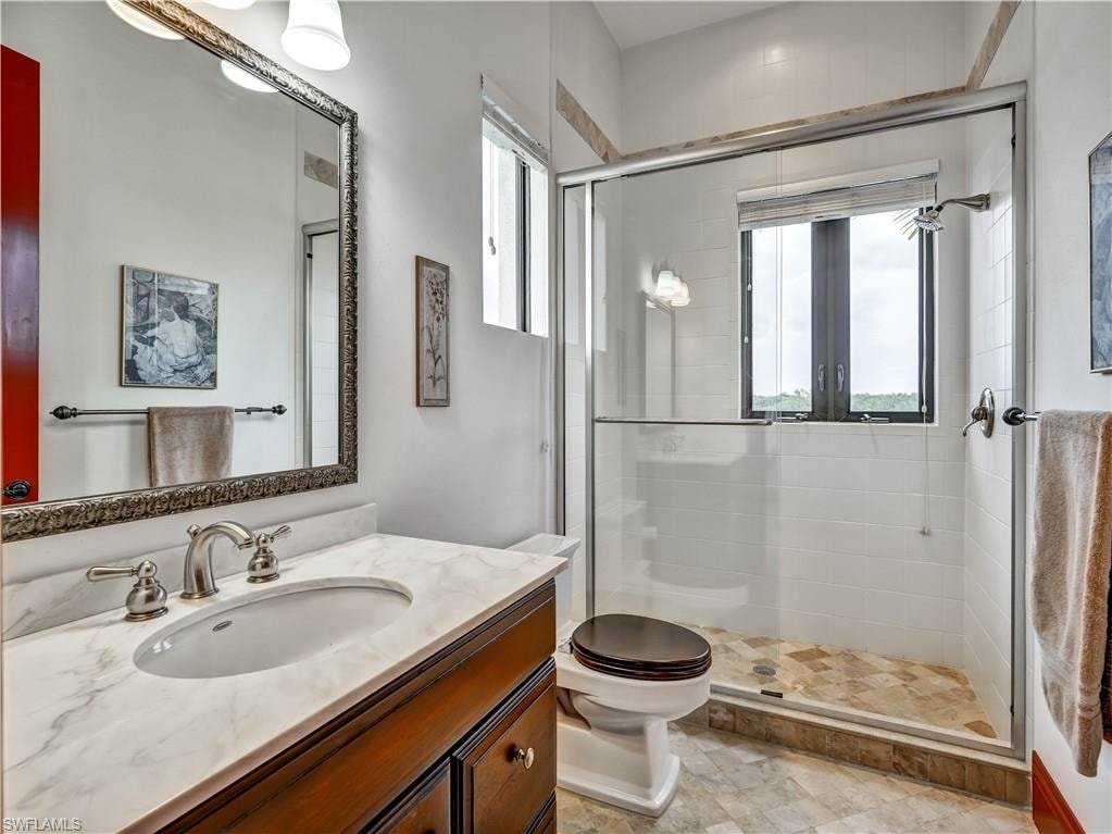 Bathroom featuring a rich wood-tone vanity with a marble-finish countertop, undermount sink, and brushed nickel fixtures