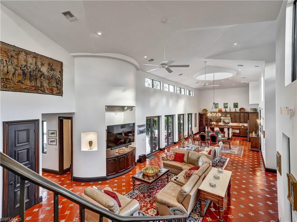 Expansive living area with high ceilings, recessed lighting, and patterned terra cotta flooring