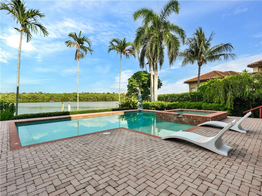 Pool area featuring a rectangular swimming pool with a spa, surrounded by paver patio decking and mature landscaping