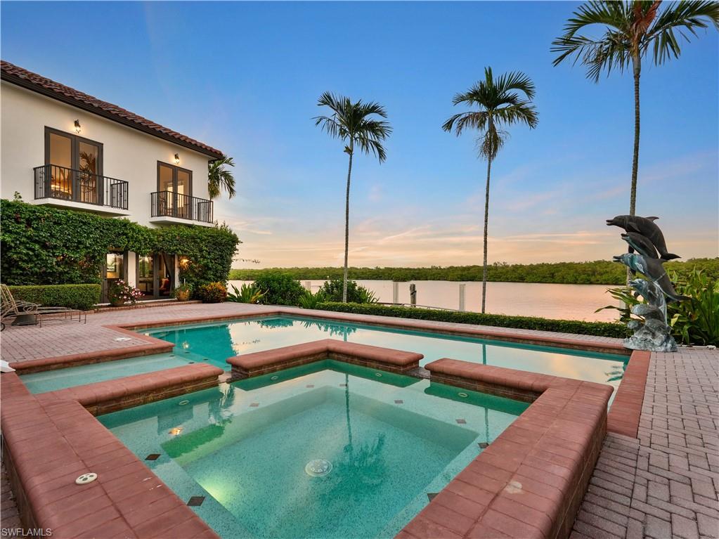 Expansive waterside brick paver patio featuring a multi-level pool and integrated spa