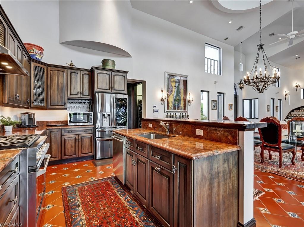 Gourmet kitchen featuring rich wood cabinetry, stainless steel appliances, and polished stone countertops