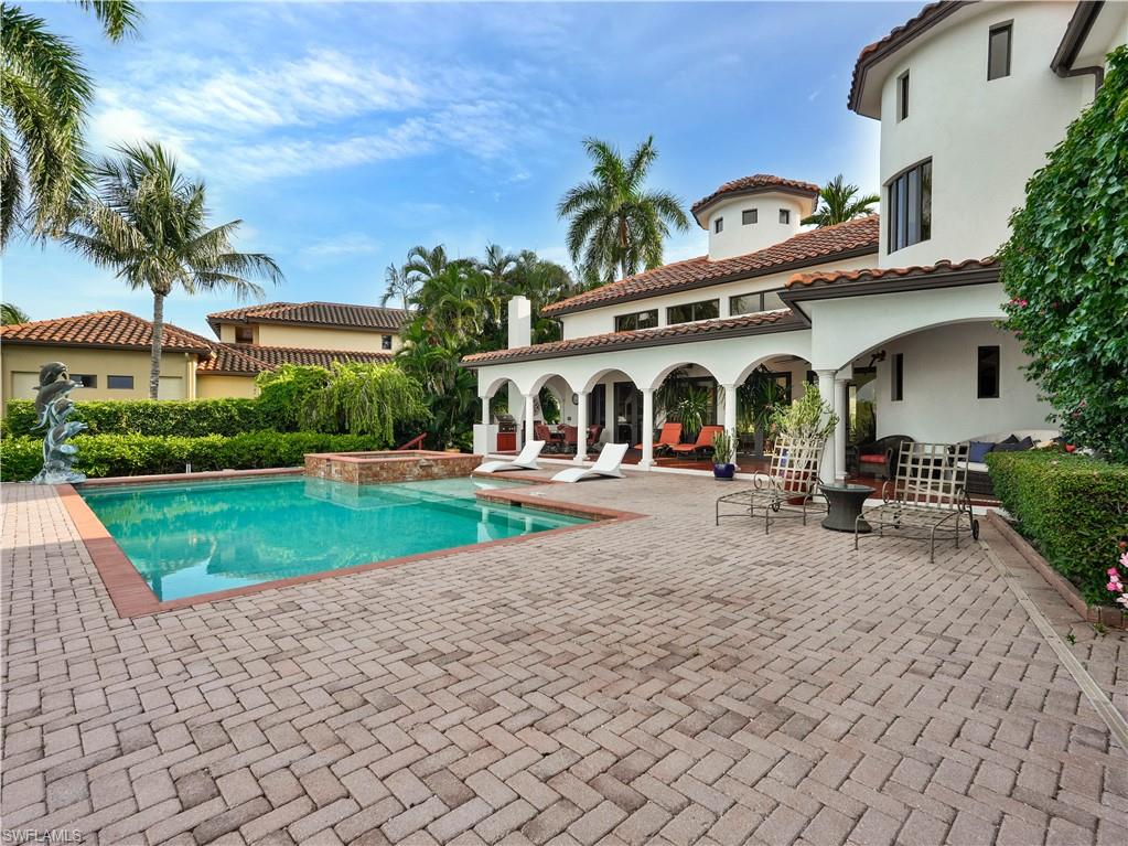 Expansive paver patio with a rectangular swimming pool featuring a brick coping and integrated spa