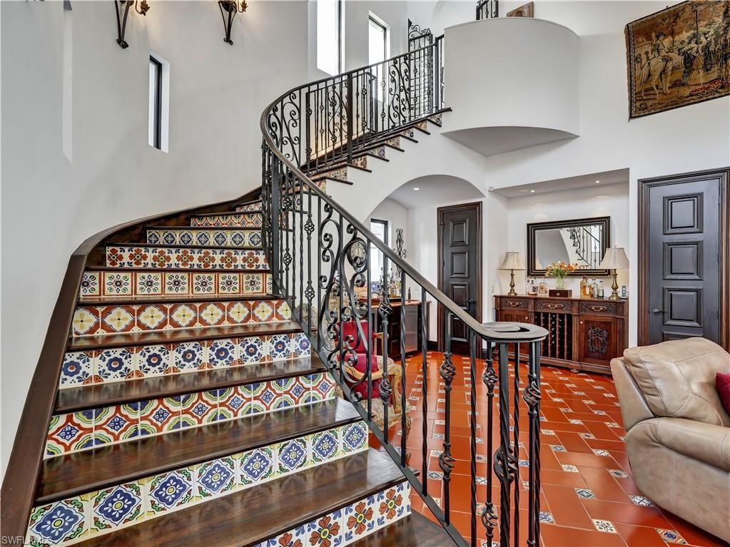 Sweeping staircase featuring decorative risers and wrought iron balusters