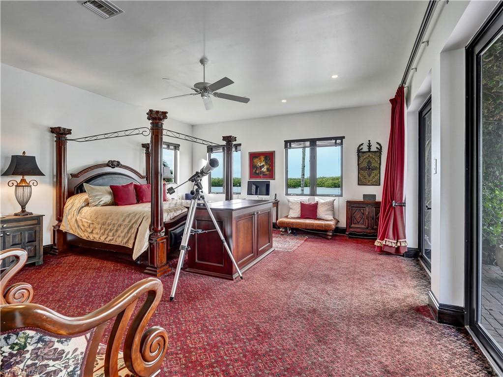 Bedroom featuring a four-poster bed, red patterned carpet, and multiple windows