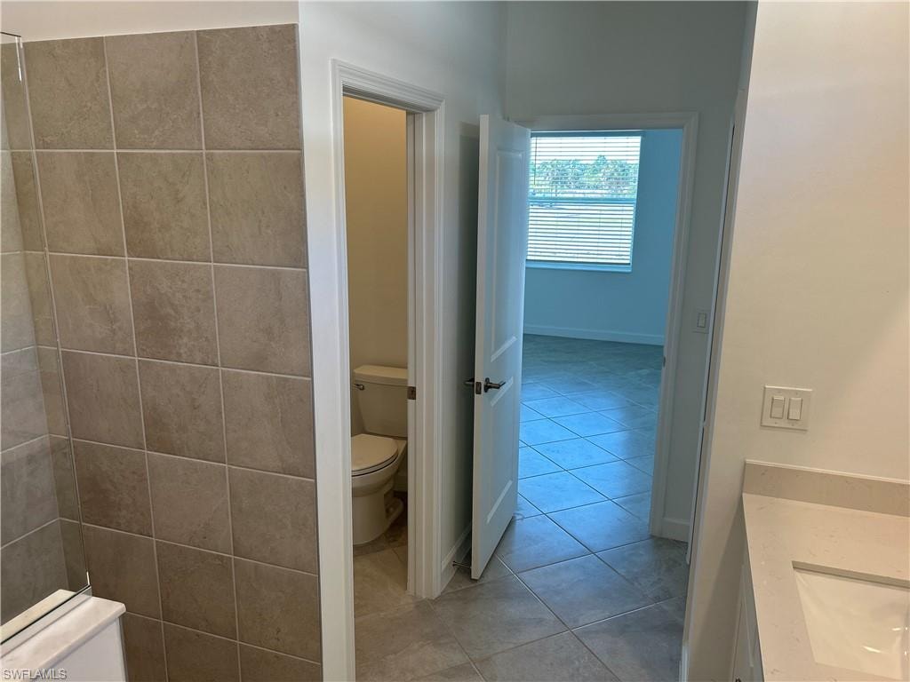 Bathroom featuring neutral-toned square wall tiles, a white vanity with a light-colored countertop, and a recessed sink