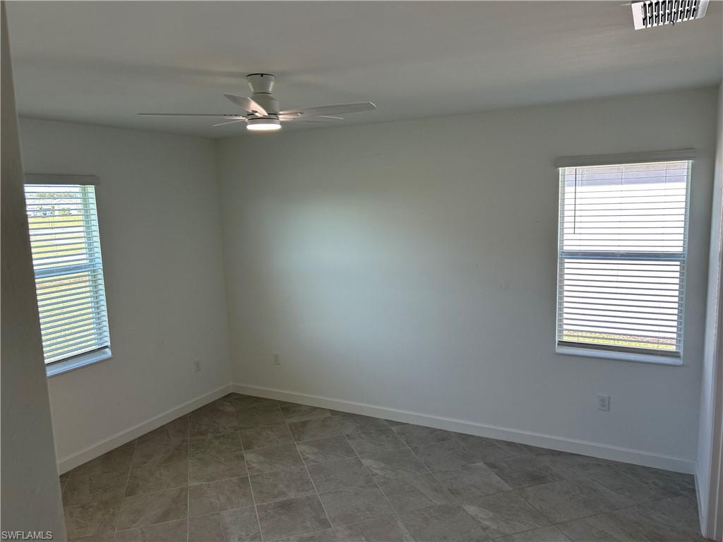 Room featuring two windows with blinds, a ceiling fan with integrated lighting, and tile flooring