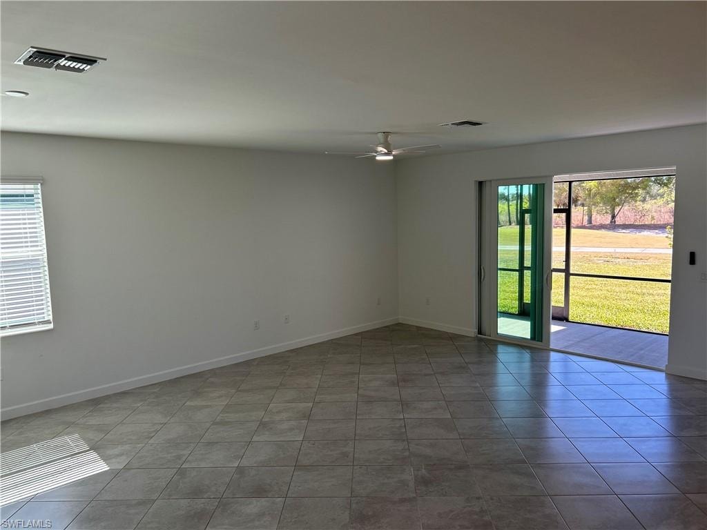 Spacious interior featuring tile flooring, a ceiling fan, and white walls