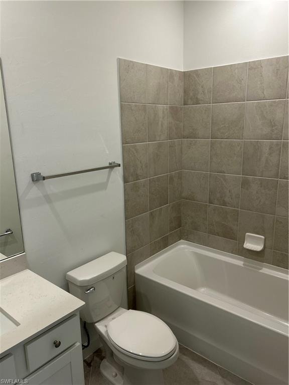 Full bathroom featuring a white porcelain tub, light-toned wall tiling, white vanity with integrated sink, and coordinating floor tiles