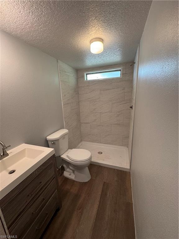 Modern bathroom featuring a wood-finish vanity with an integrated sink, a white toilet, and a walk-in shower with tiled walls
