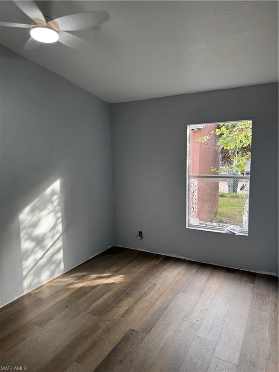 Room featuring wood-finish flooring, a ceiling fan with integrated lighting, and a window providing natural illumination