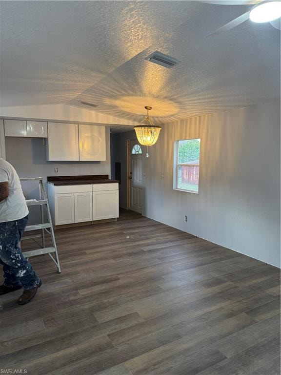 Open-concept living space featuring wood-finish flooring, a contemporary chandelier, and a ceiling fan
