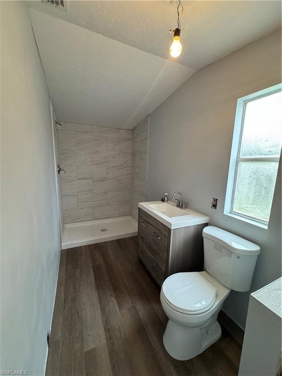 Bathroom featuring wood-finish flooring, a contemporary vanity with an integrated sink, and a tiled shower enclosure with a white shower pan