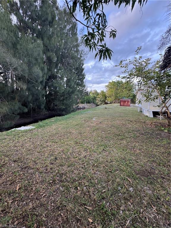 Expansive grassy area featuring mature trees along the perimeter and a red storage shed