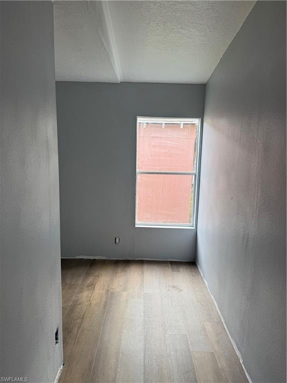Room featuring a single window, light gray painted walls, and wood-finish flooring