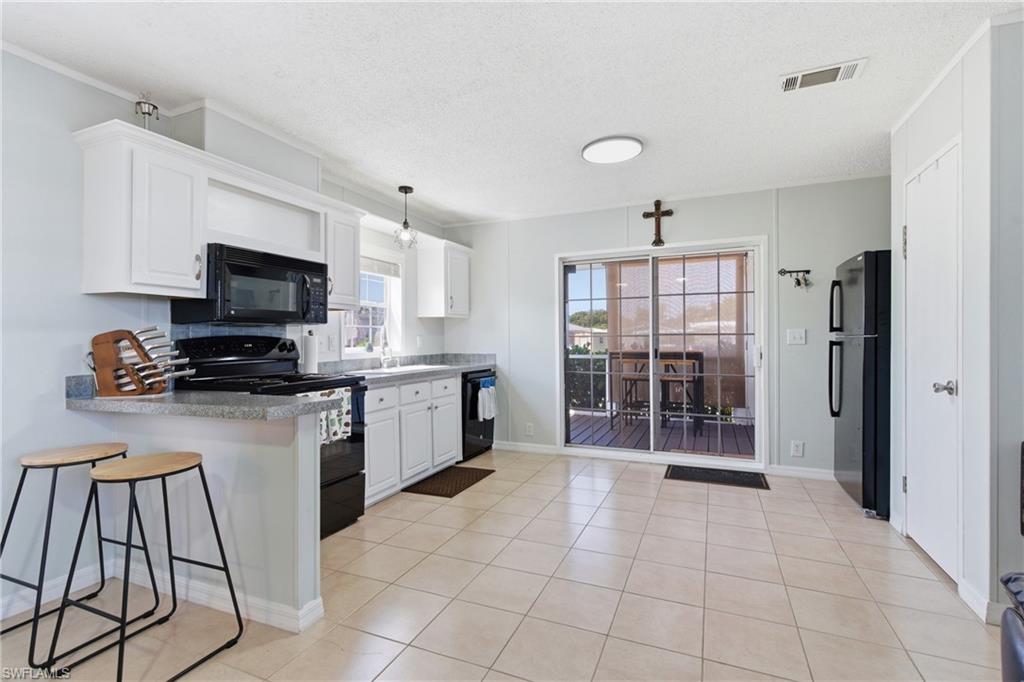Kitchen featuring light-finish cabinetry, black appliances, stone-finish countertops, and tile flooring