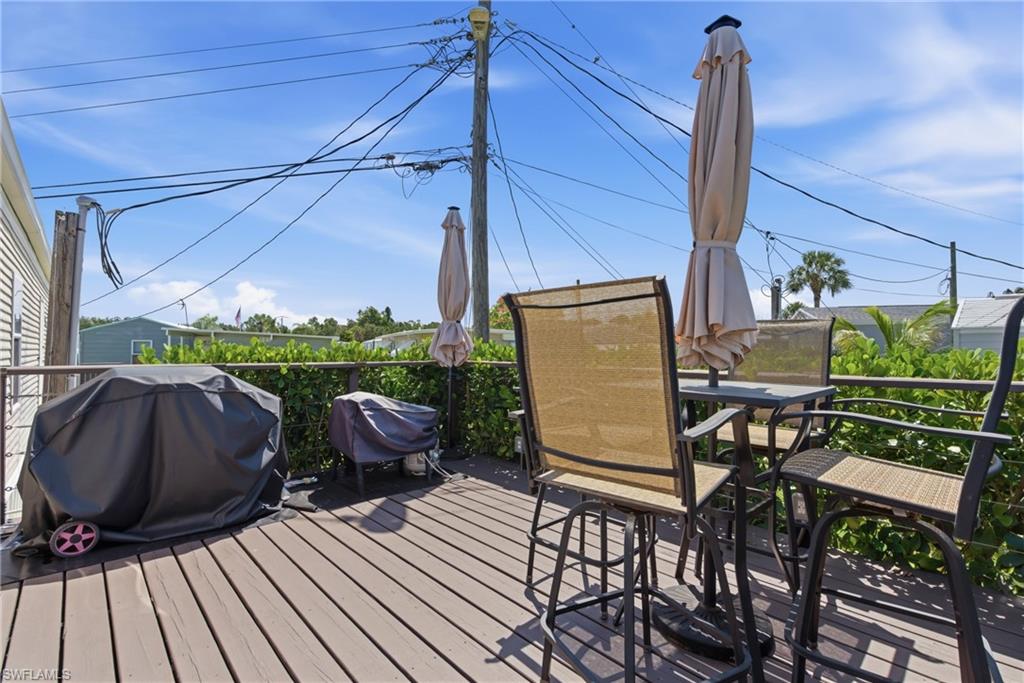 Expansive outdoor deck featuring wood-finish flooring, a metal railing, and privacy landscaping
