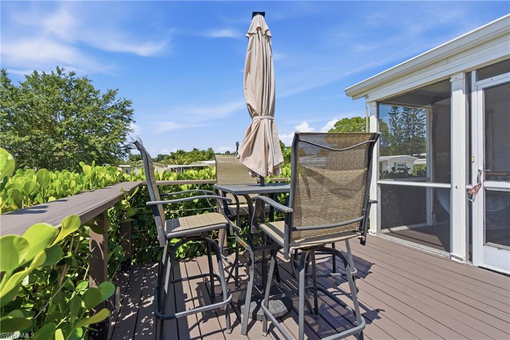Private outdoor deck featuring composite wood-finish flooring, a screened enclosure access point, and established perimeter foliage