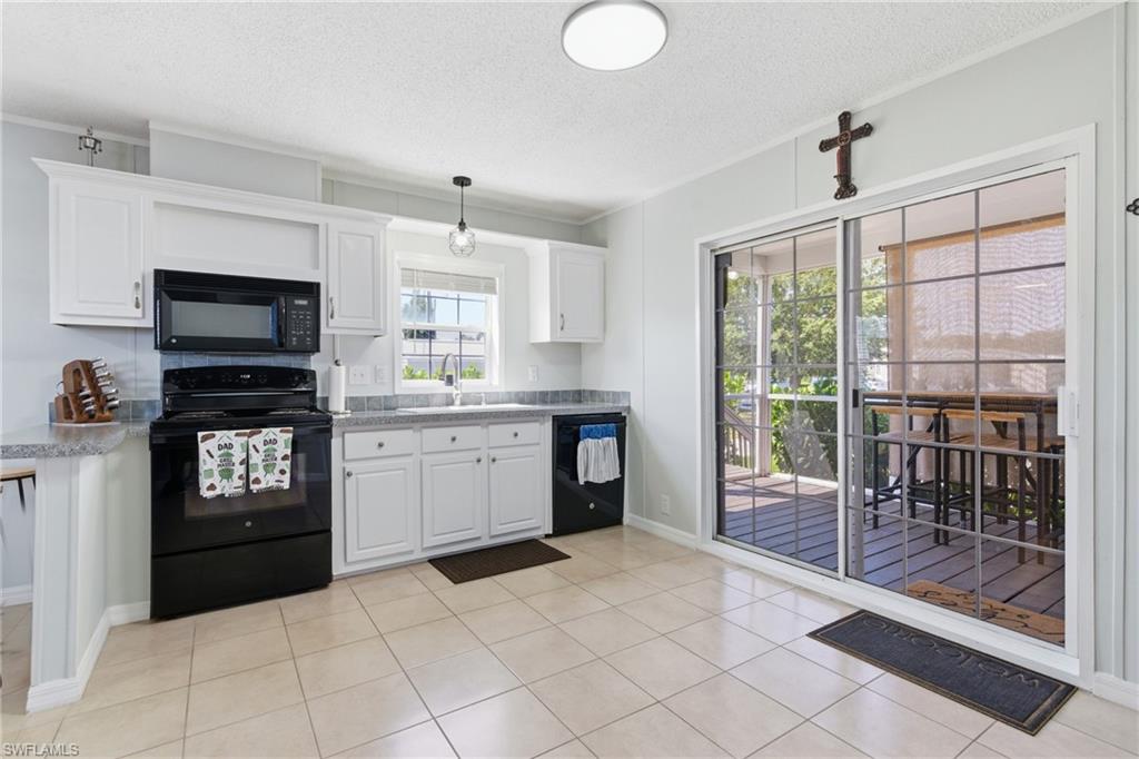 Kitchen featuring white cabinetry, grey speckled countertops, tile flooring, and sliding glass doors to the exterior