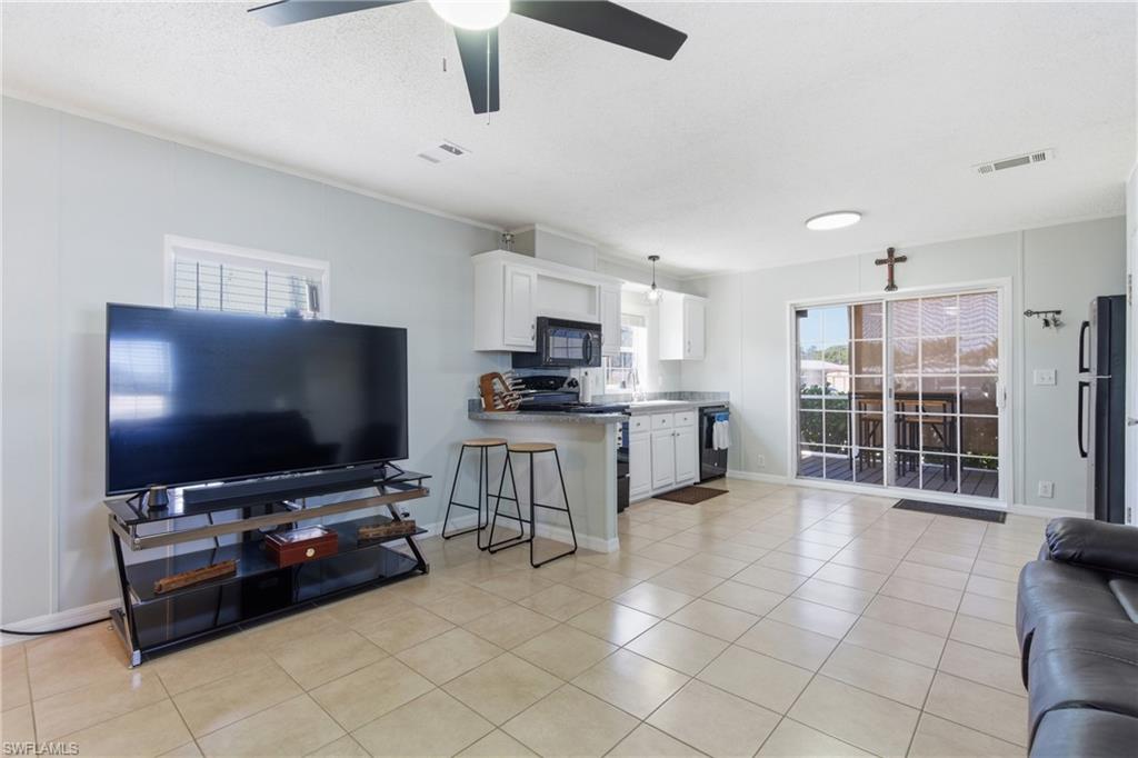 Open-concept living space featuring light-toned tile flooring, light gray wall paint, and a modern ceiling fan