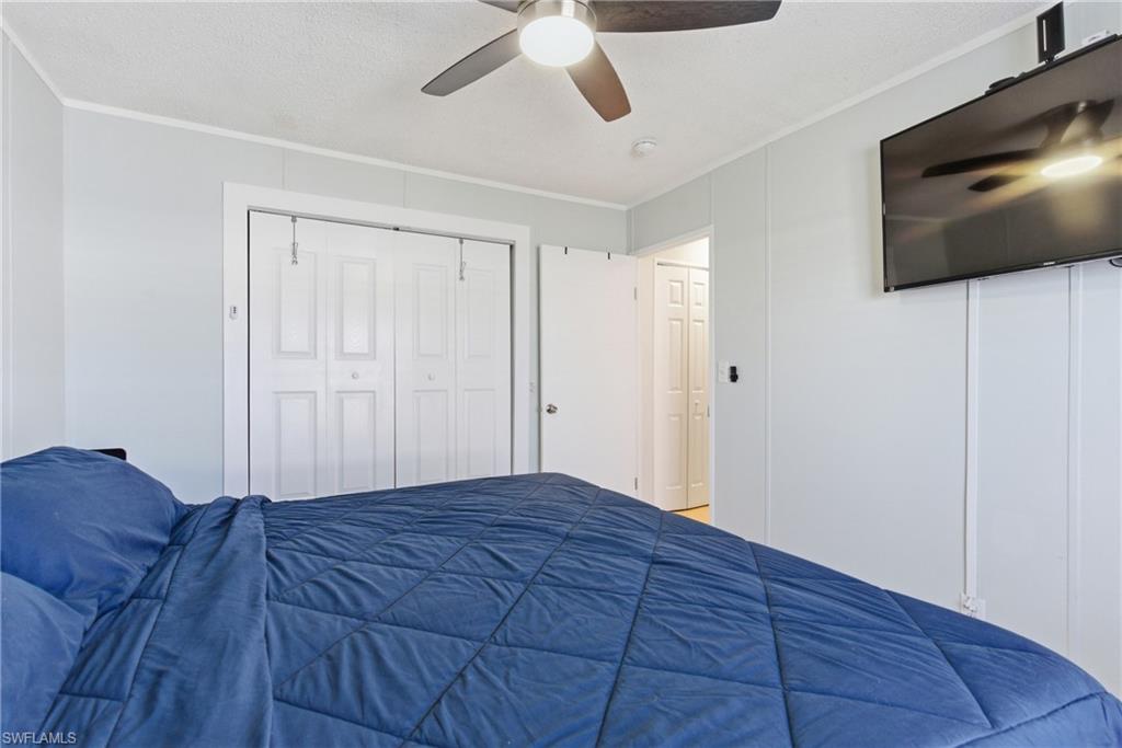 Room featuring a ceiling fan with integrated lighting, wall-mounted television, white paneled walls, and bi-fold closet doors