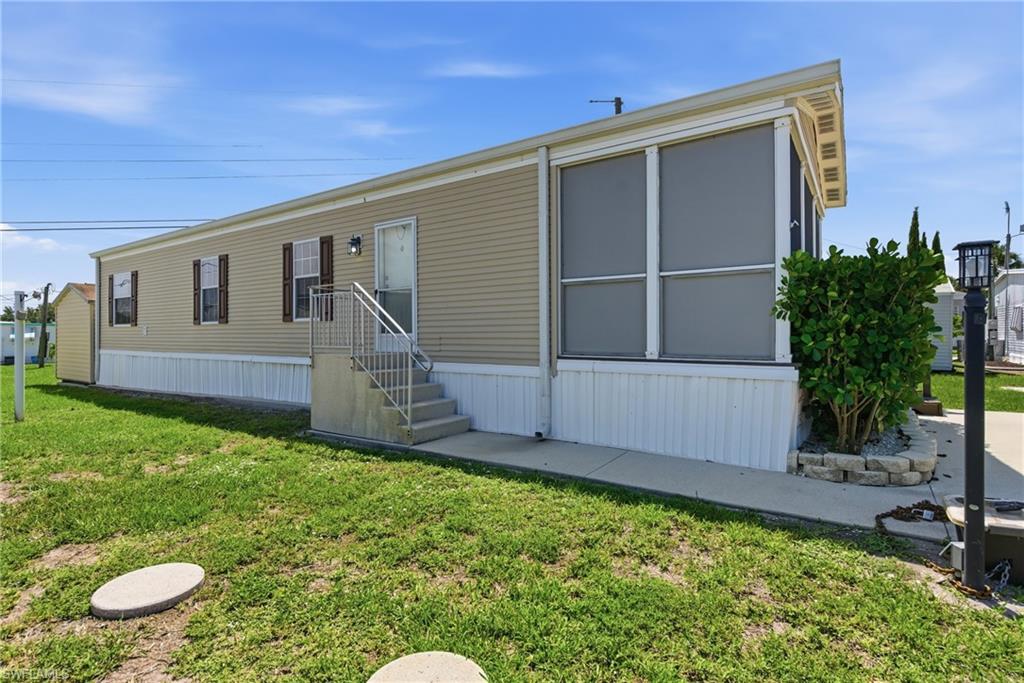 Single-story residence featuring light-colored siding, a screened-in lanai, and side door with steps