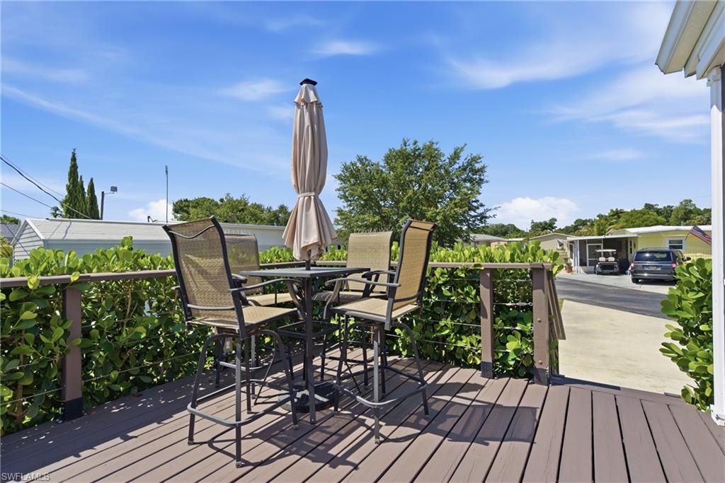 Spacious outdoor deck with composite wood-finish flooring, featuring a sturdy railing system and dense perimeter shrubbery