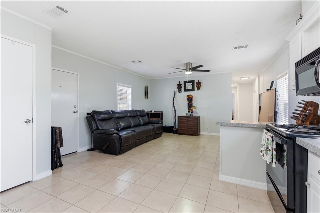 Open-concept living space featuring neutral tile flooring, a ceiling fan, and light gray wall tones