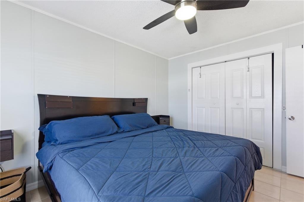 Room featuring light-colored paneled walls, a ceiling fan with integrated lighting, and neutral tile flooring
